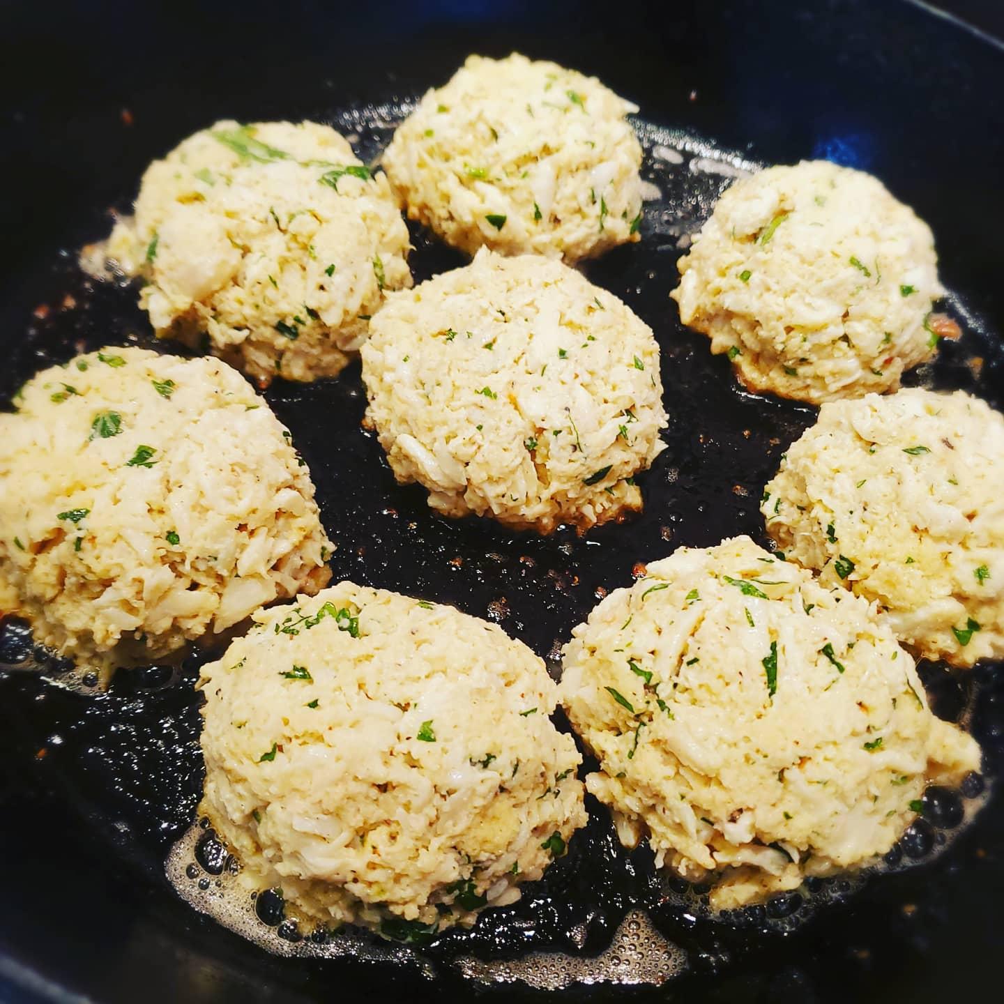 Crab cakes searing in a pan during Dragonfly Catering kitchen prep