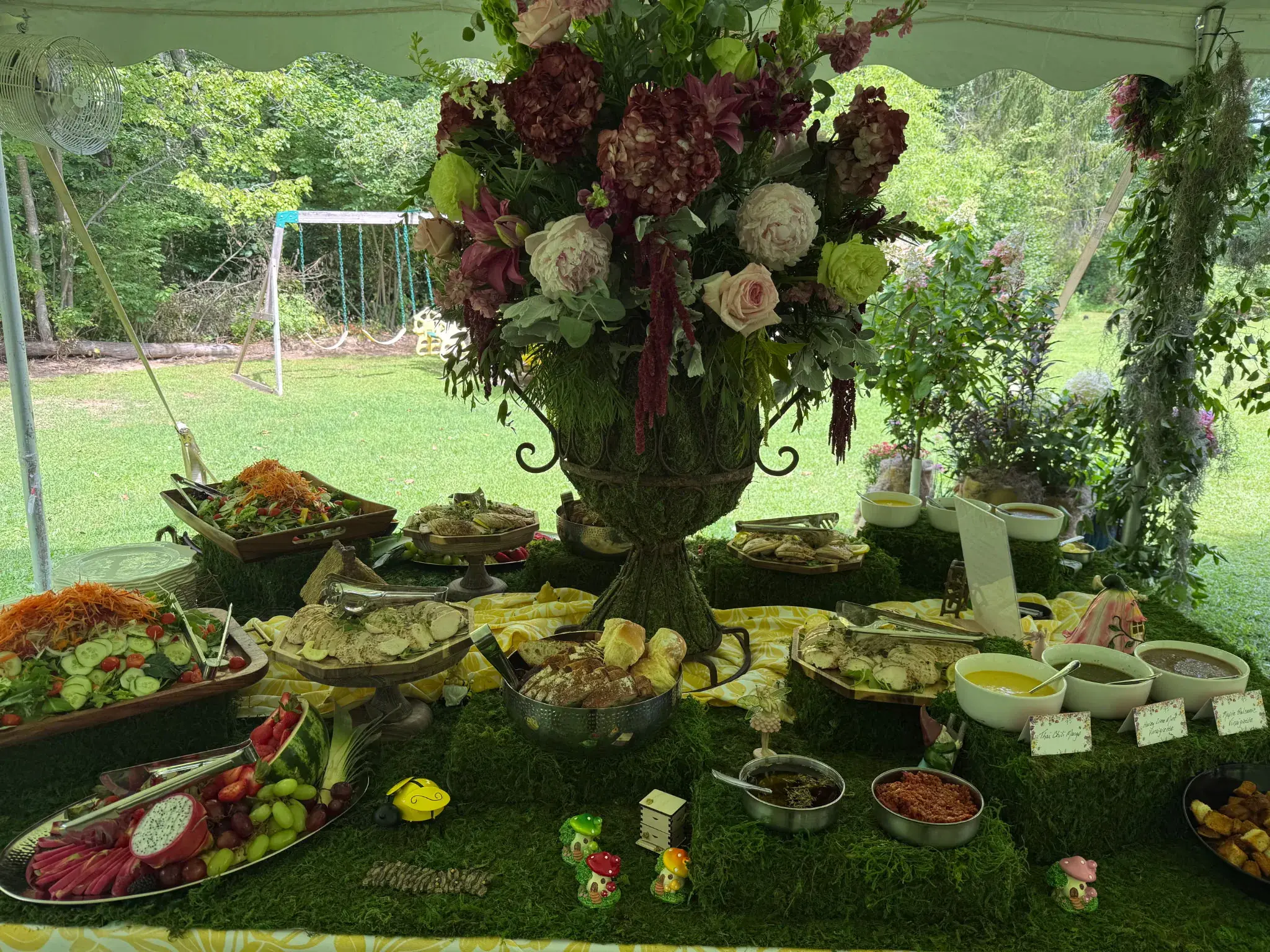 An enchanted garden buffet with a towering floral arrangement styled by Dragonfly Catering