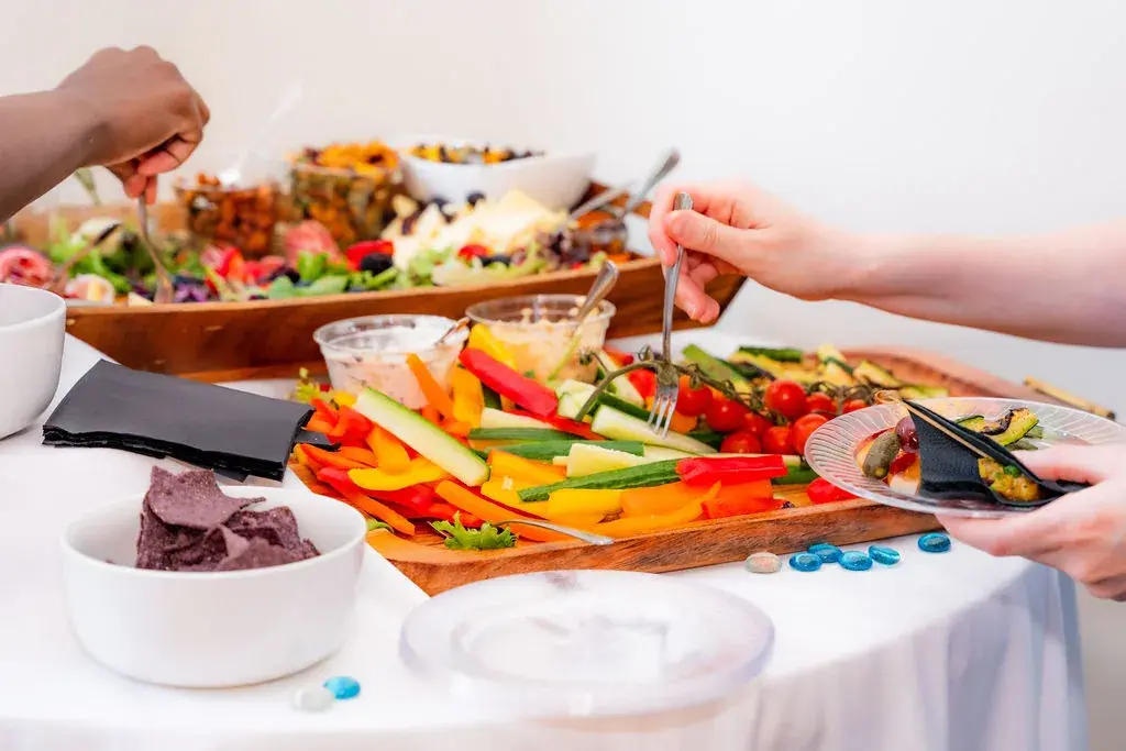 Guests serving vegetables and appetizers from a colorful Dragonfly Catering grazing buffet