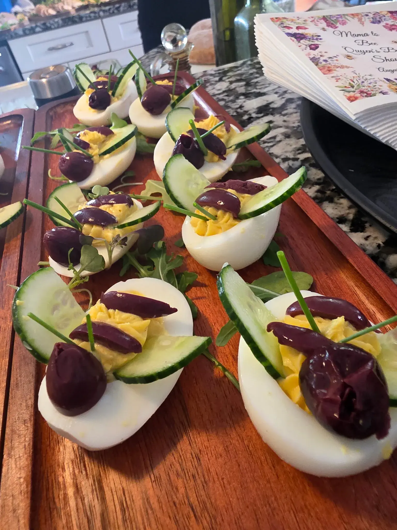 Mediterranean deviled eggs garnished with cucumber, olives, and chives by Dragonfly Catering